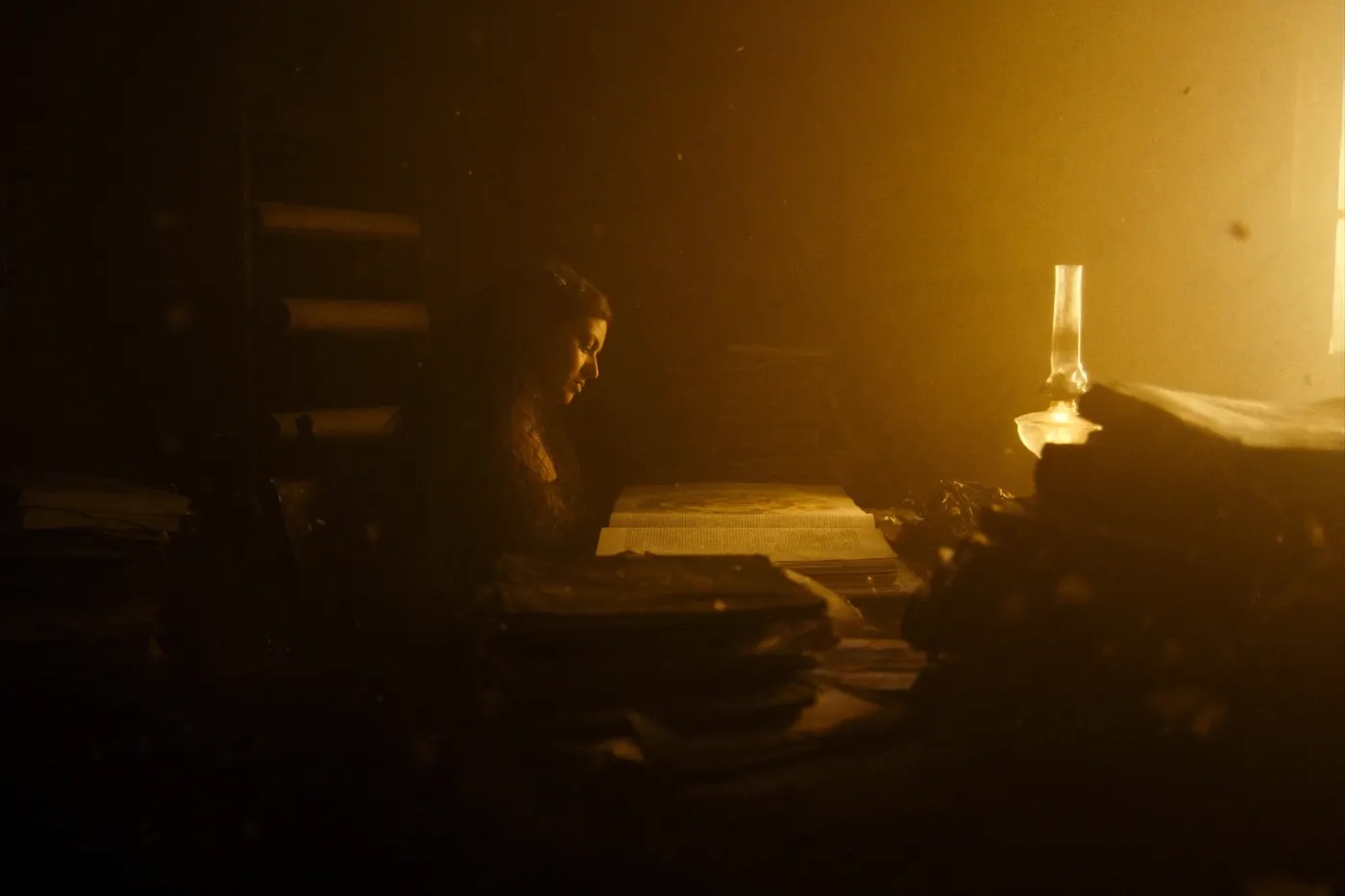 A woman reading an ancient manuscript by warm lamplight
